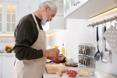 Photo of Elderly man cooking at countertop in kitchen