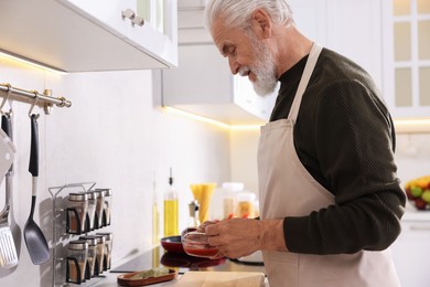Photo of Elderly man cooking at countertop in kitchen