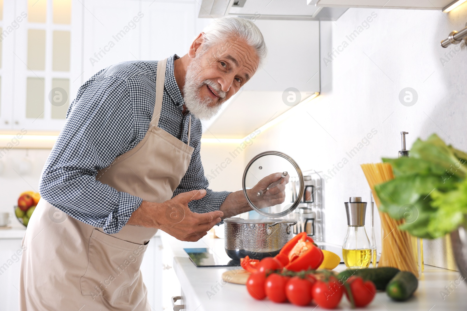 Elderly man cooking dish on cooktop in kitchen Photo of Elderly man cooking dish on cooktop in kitchen