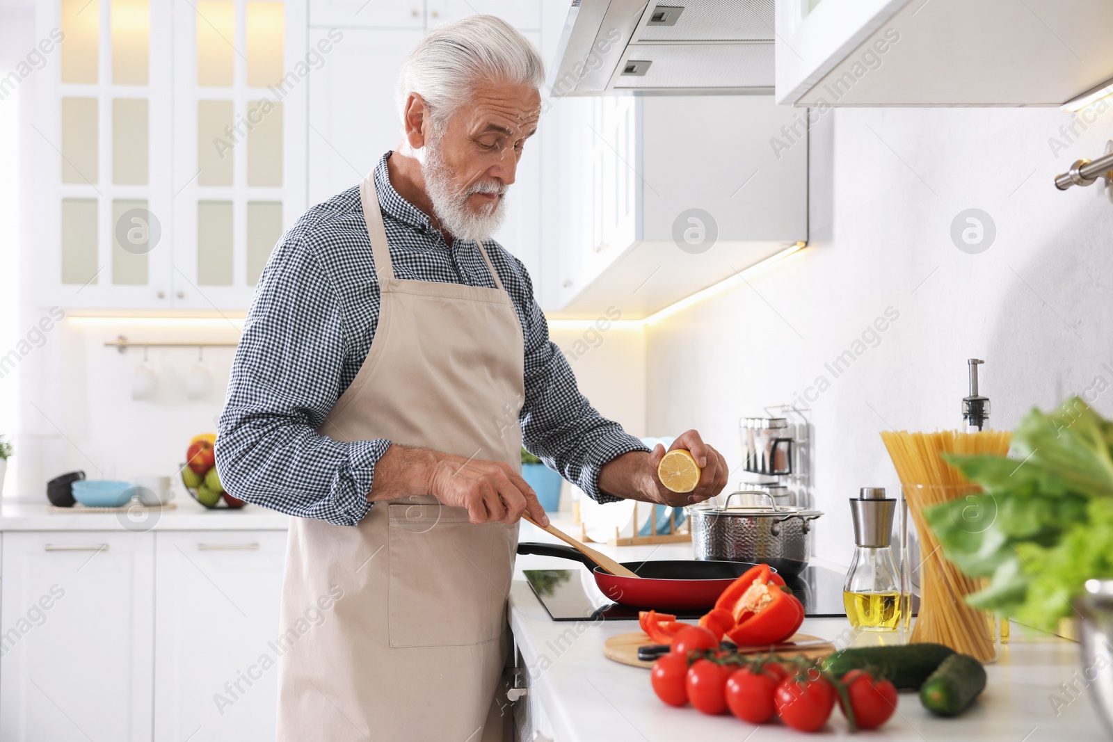 Elderly man cooking dish on cooktop in kitchen Photo of Elderly man cooking dish on cooktop in kitchen