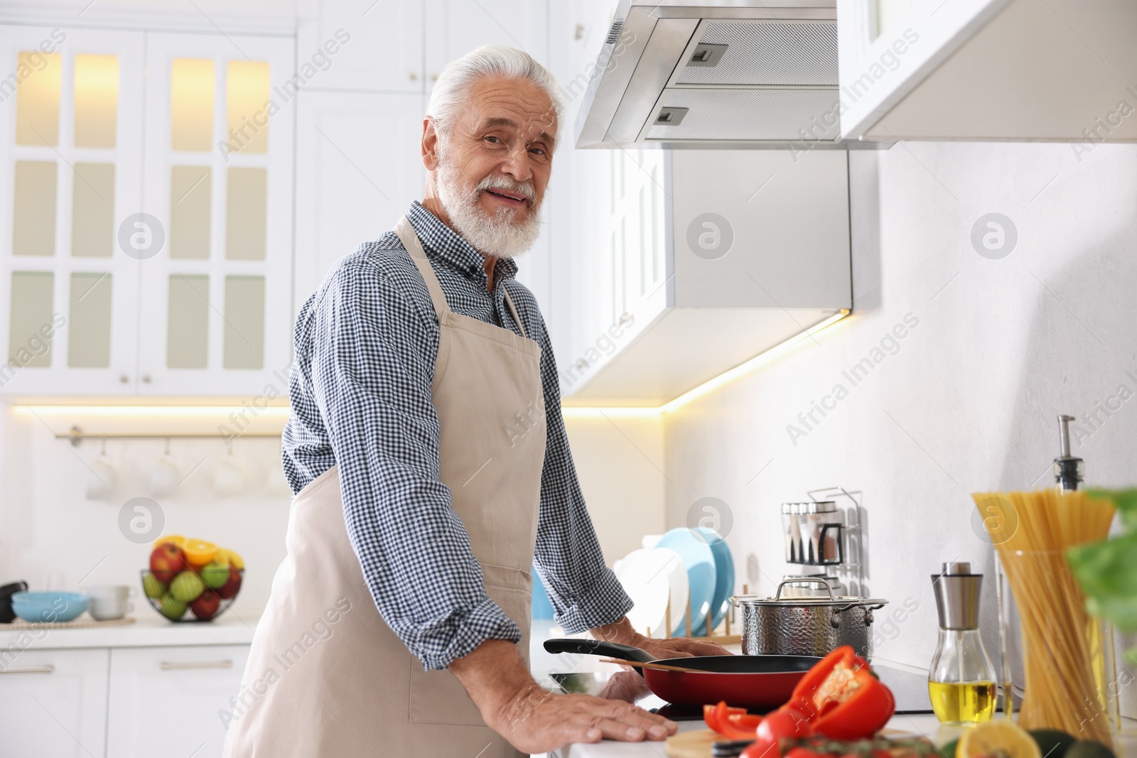 Elderly man cooking dish on cooktop in kitchen Photo of Elderly man cooking dish on cooktop in kitchen