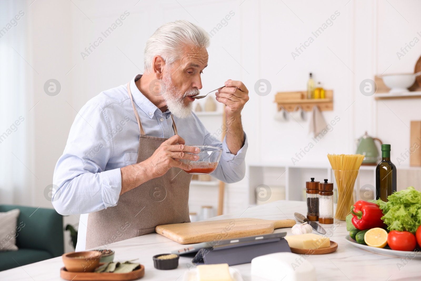 Elderly man cooking at white marble table in kitchen Photo of Elderly man cooking at white marble table in kitchen