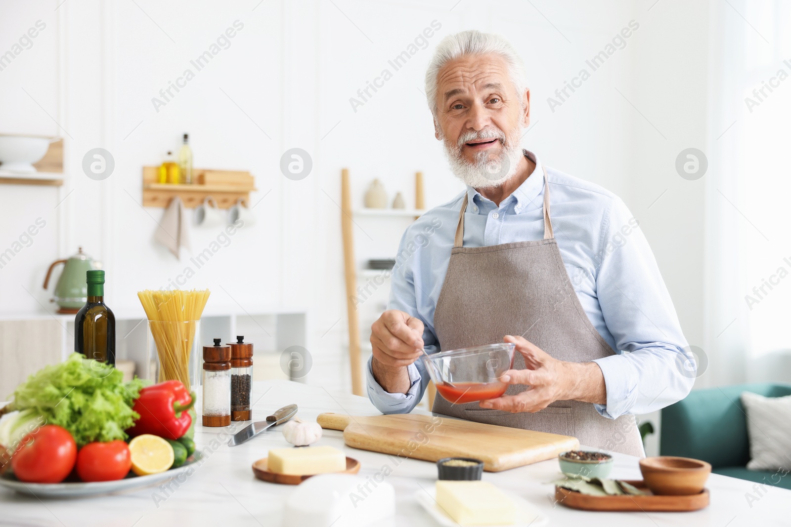 Elderly man cooking at white marble table in kitchen Photo of Elderly man cooking at white marble table in kitchen