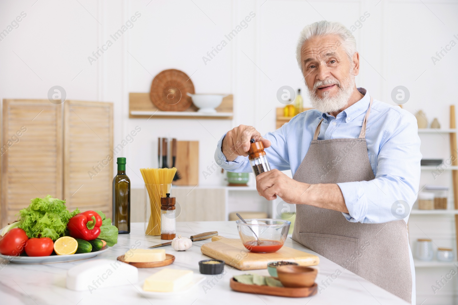 Elderly man cooking at white marble table in kitchen Photo of Elderly man cooking at white marble table in kitchen