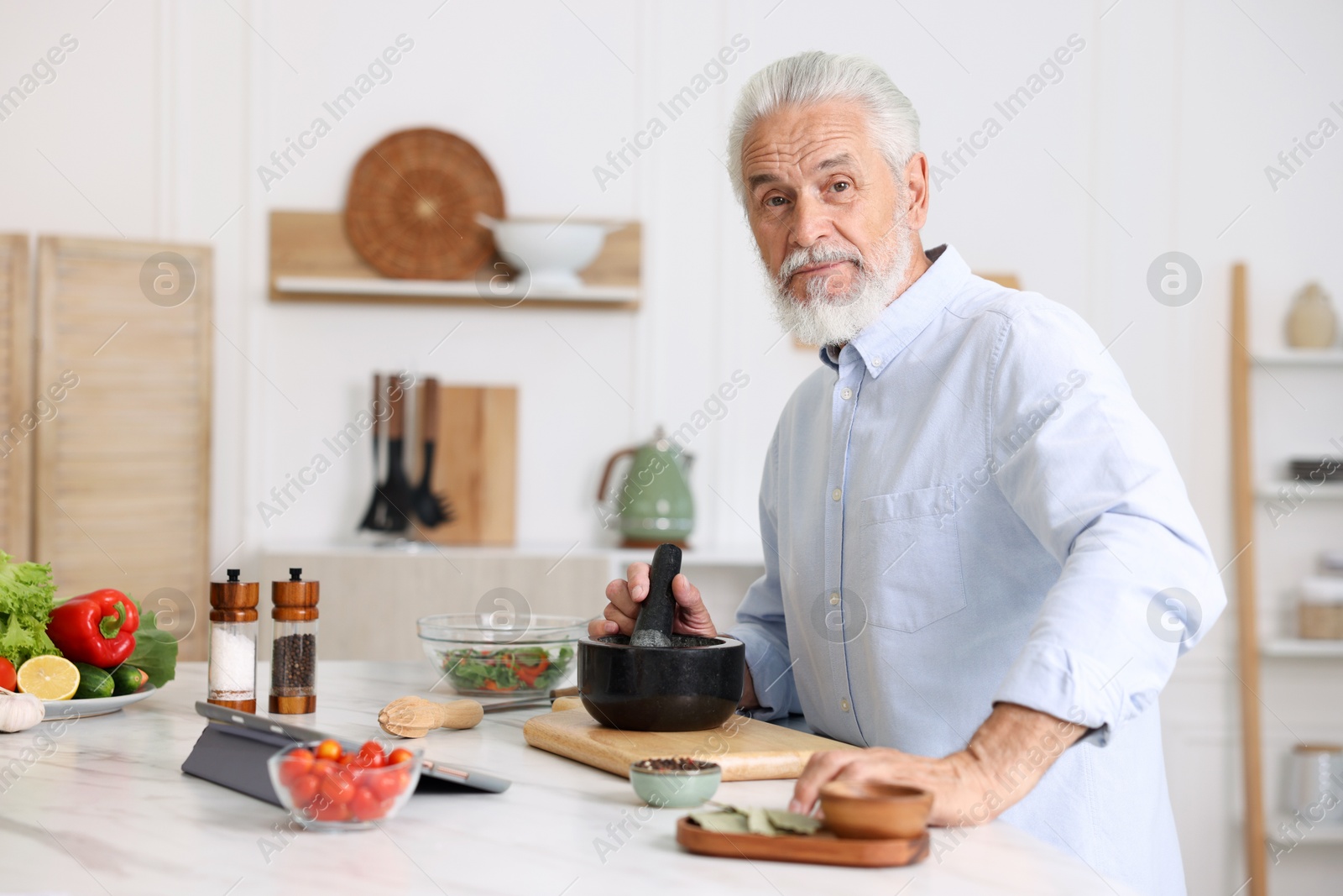 Elderly man cooking at white marble table in kitchen Photo of Elderly man cooking at white marble table in kitchen
