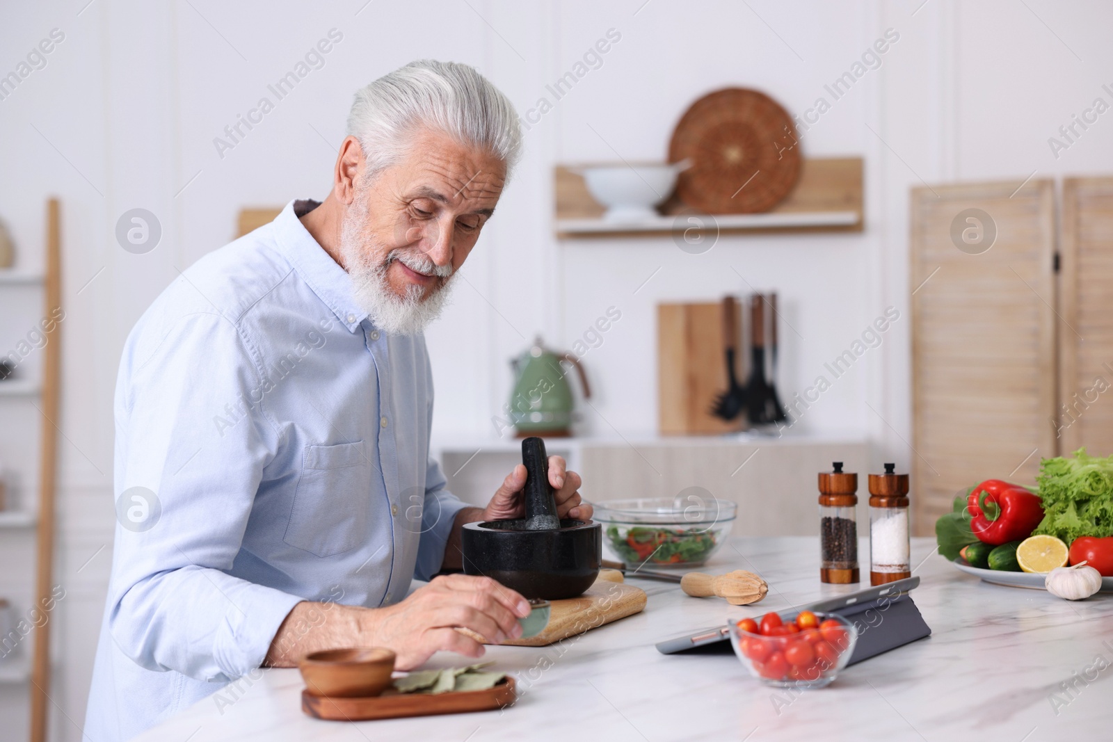 Elderly man cooking at white marble table in kitchen Photo of Elderly man cooking at white marble table in kitchen