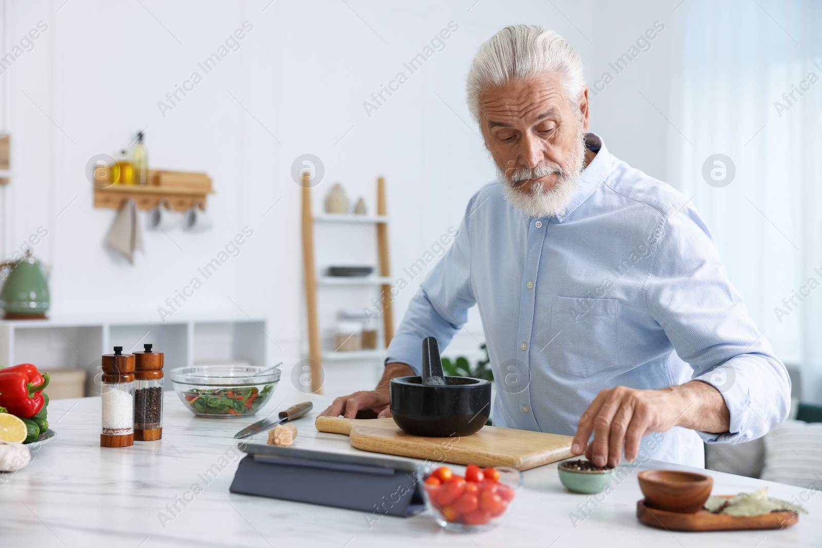 Elderly man cooking at white marble table in kitchen Photo of Elderly man cooking at white marble table in kitchen