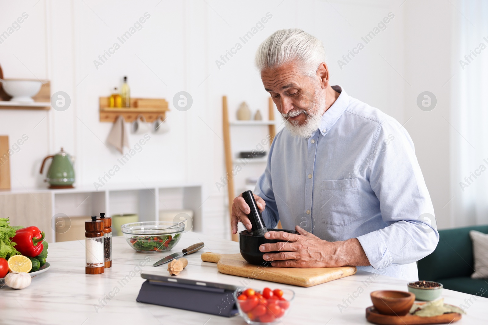Elderly man cooking at white marble table in kitchen Photo of Elderly man cooking at white marble table in kitchen