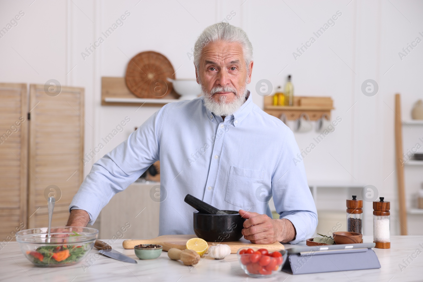 Elderly man cooking at white marble table in kitchen Photo of Elderly man cooking at white marble table in kitchen