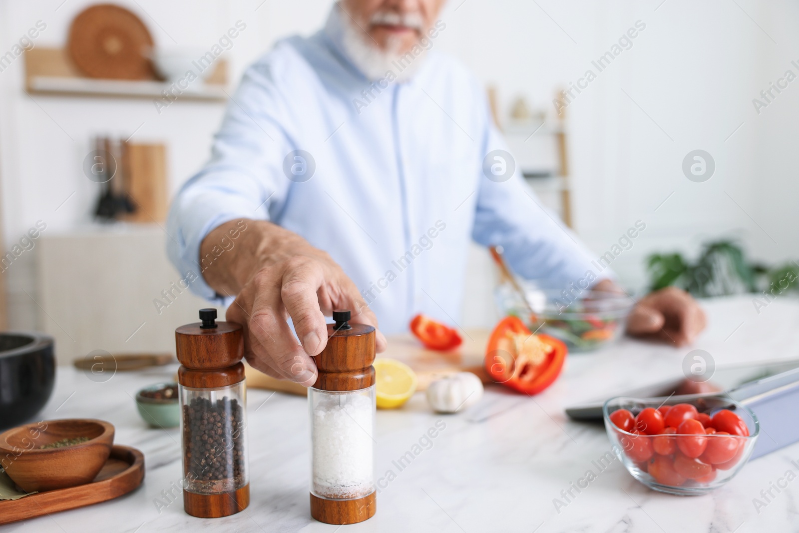 Elderly man cooking at white marble table in kitchen, closeup Photo of Elderly man cooking at white marble table in kitchen, closeup