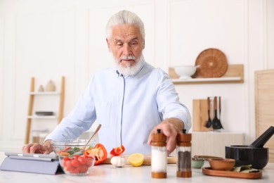 Photo of Elderly man cooking at white marble table in kitchen