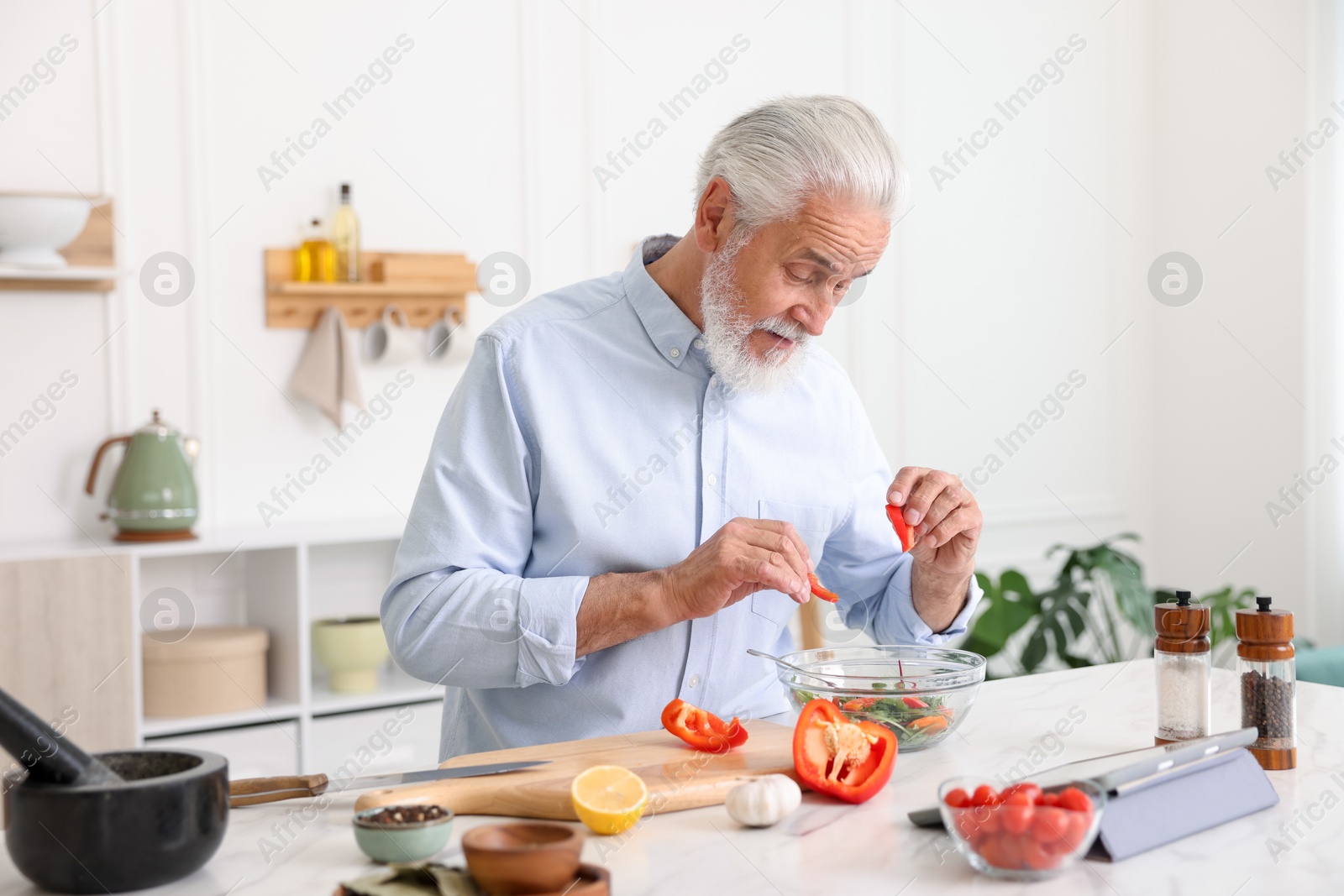 Elderly man cooking at white marble table in kitchen Photo of Elderly man cooking at white marble table in kitchen