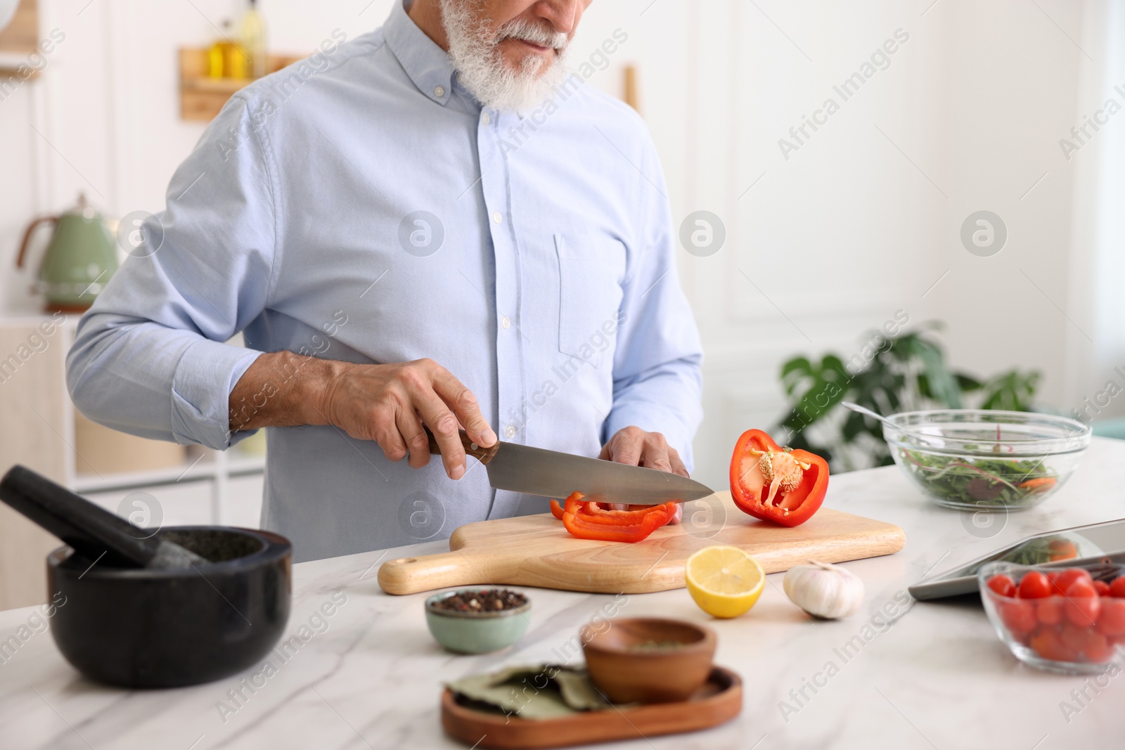 Elderly man cooking at white marble table in kitchen, closeup Photo of Elderly man cooking at white marble table in kitchen, closeup