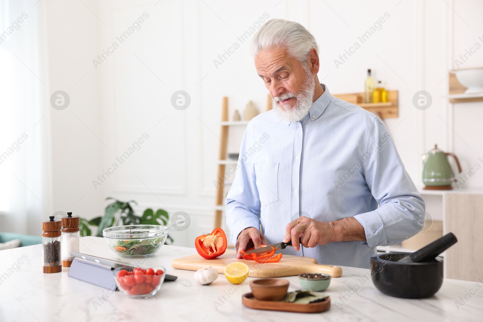 Elderly man cooking at white marble table in kitchen Photo of Elderly man cooking at white marble table in kitchen