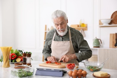 Photo of Elderly man cooking at white marble table in kitchen