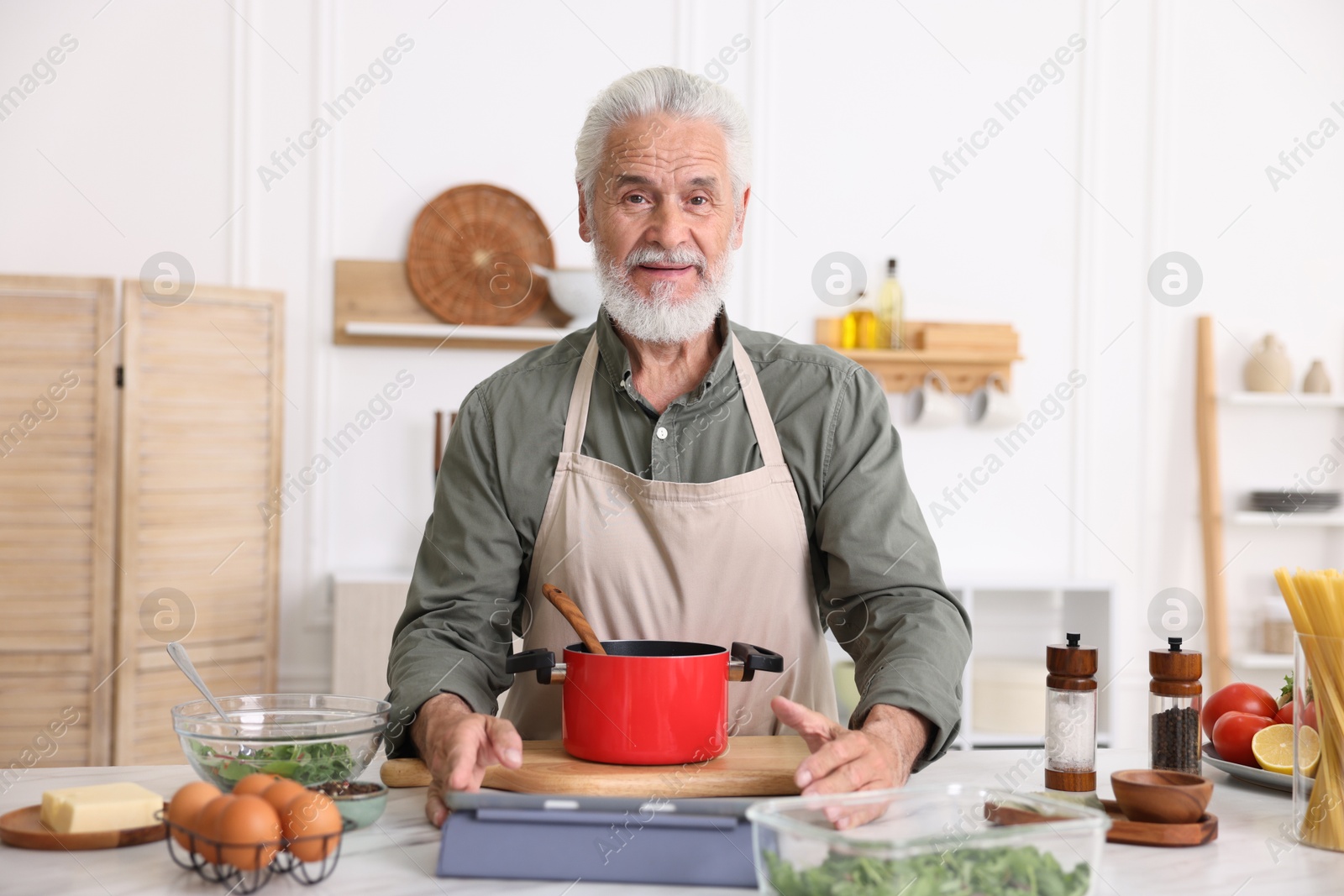 Elderly man cooking at white marble table in kitchen Photo of Elderly man cooking at white marble table in kitchen