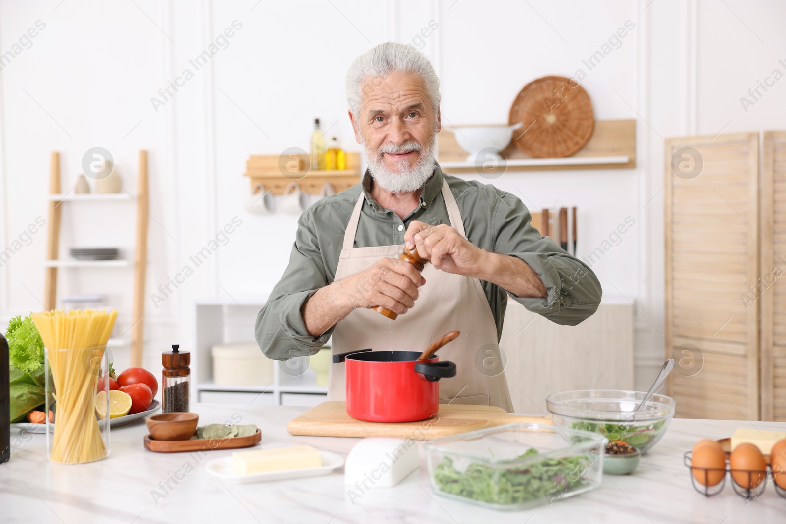 Elderly man cooking at white marble table in kitchen Photo of Elderly man cooking at white marble table in kitchen