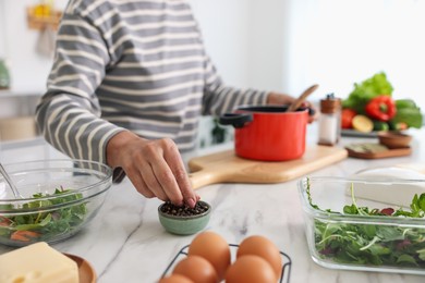 Photo of Senior woman cooking at white marble table in kitchen, closeup