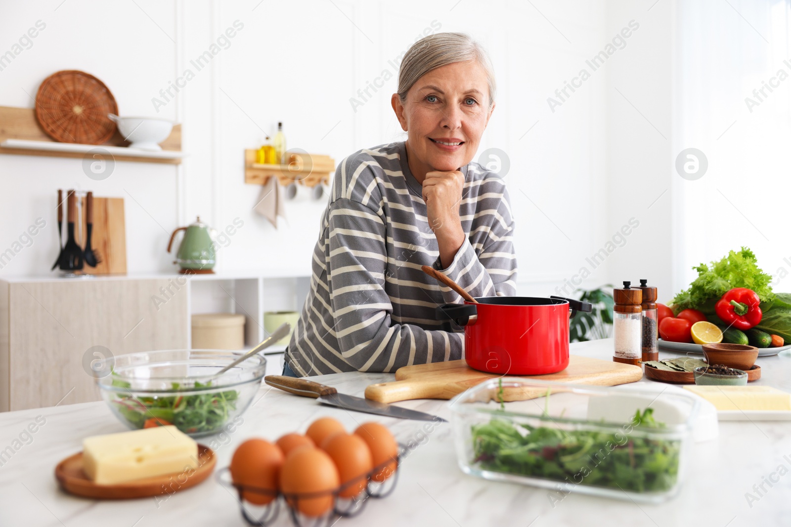 Senior woman cooking at white marble table in kitchen Photo of Senior woman cooking at white marble table in kitchen