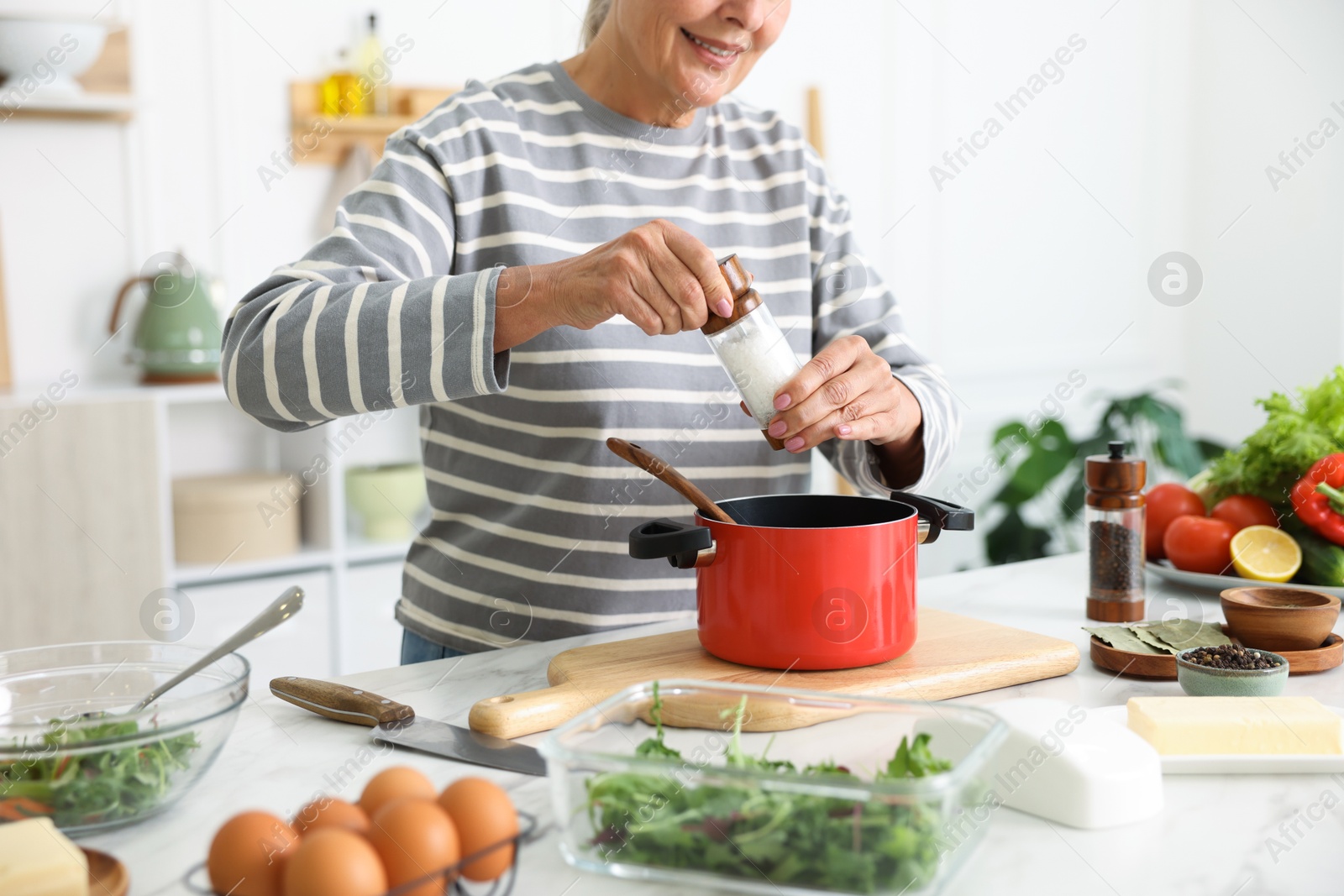 Senior woman cooking at white marble table in kitchen, closeup Photo of Senior woman cooking at white marble table in kitchen, closeup