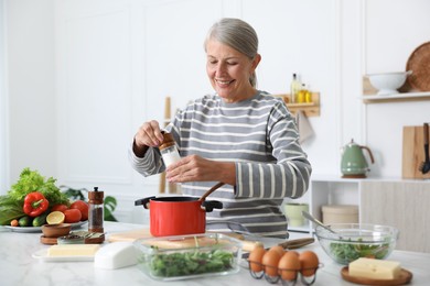 Photo of Senior woman cooking at white marble table in kitchen