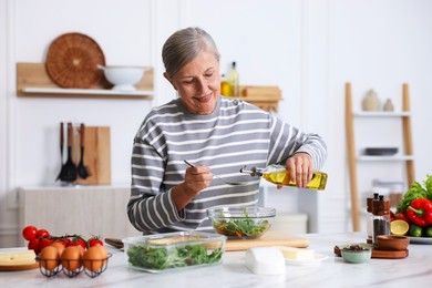 Photo of Senior woman cooking salad at white marble table in kitchen