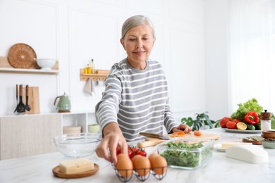 Photo of Senior woman cooking at white marble table in kitchen