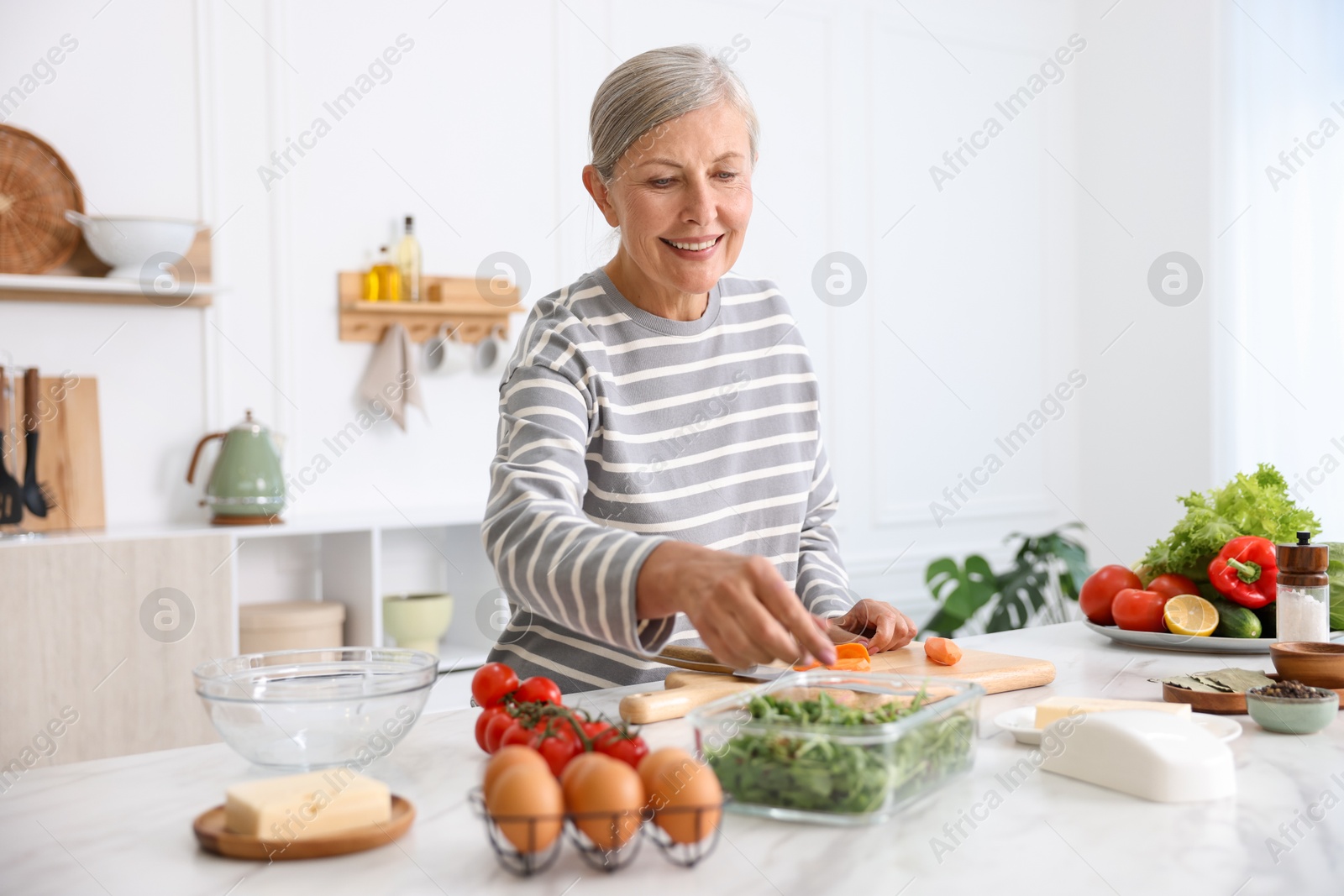 Senior woman cooking at white marble table in kitchen Photo of Senior woman cooking at white marble table in kitchen