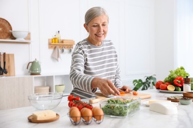 Photo of Senior woman cooking at white marble table in kitchen