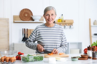 Photo of Senior woman cooking at white marble table in kitchen