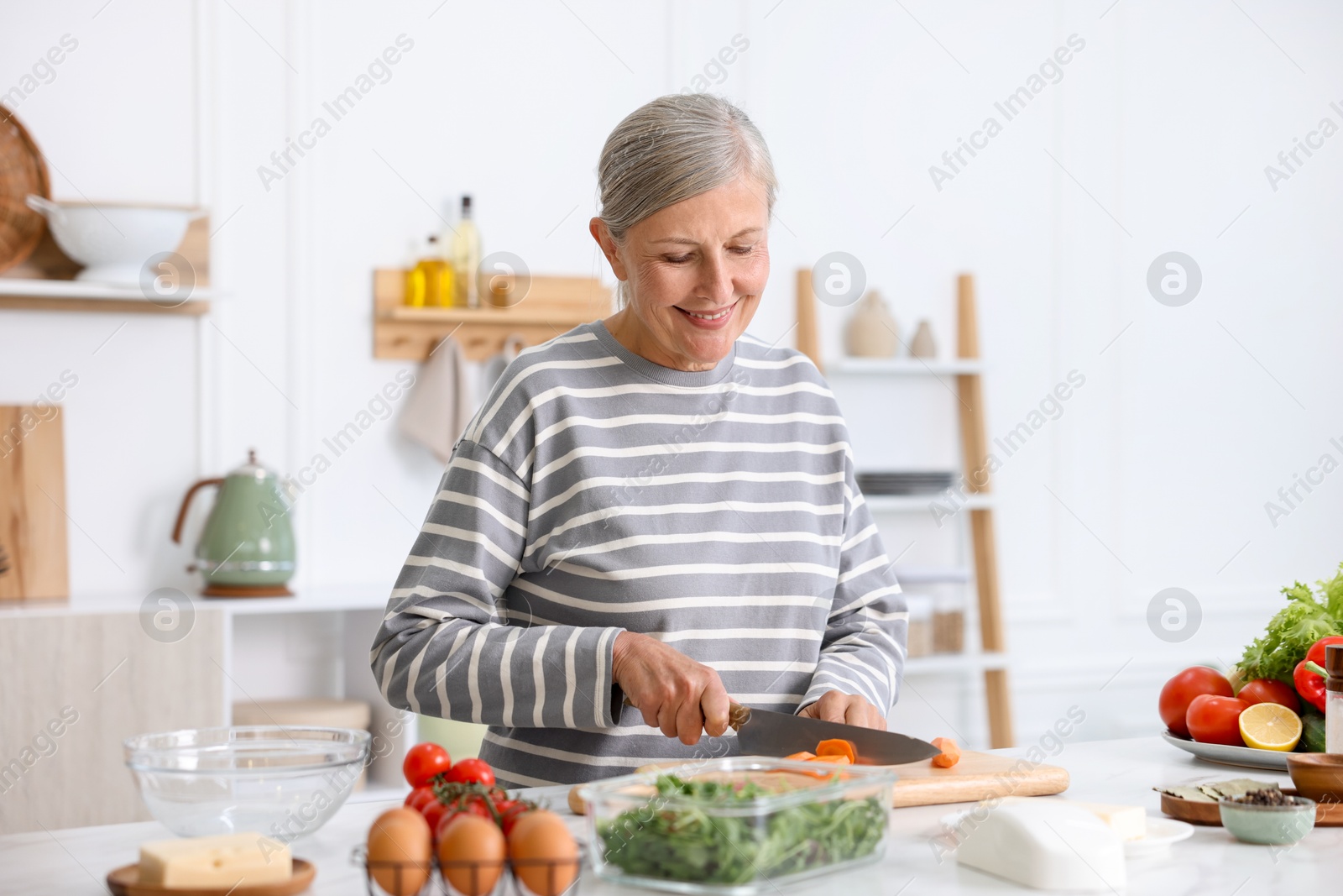 Senior woman cooking at white marble table in kitchen Photo of Senior woman cooking at white marble table in kitchen