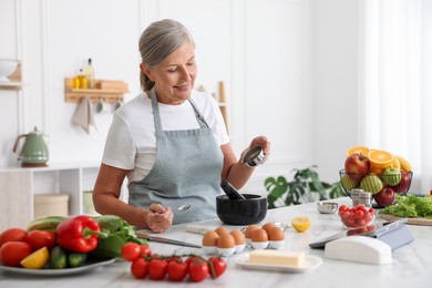 Photo of Senior woman cooking at white marble table in kitchen