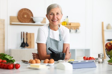 Photo of Senior woman cooking at white marble table in kitchen