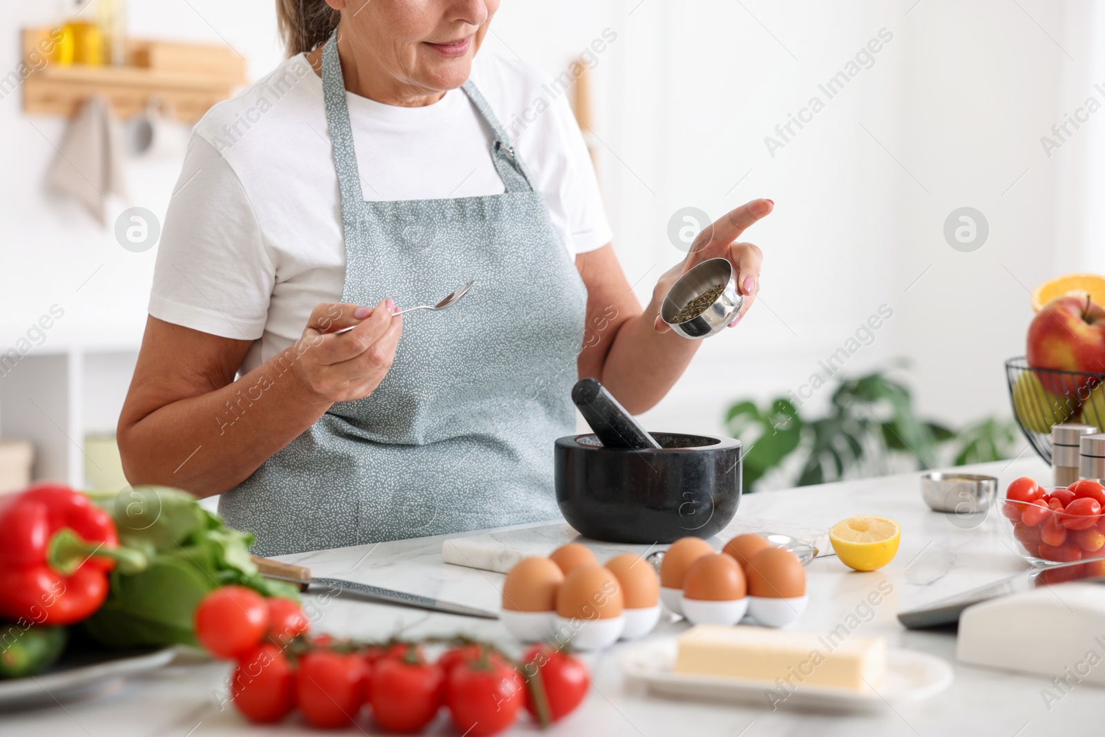 Senior woman cooking at white marble table in kitchen, closeup Photo of Senior woman cooking at white marble table in kitchen, closeup