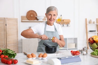 Photo of Senior woman cooking at white marble table in kitchen