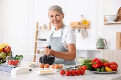 Photo of Senior woman cooking at white marble table in kitchen