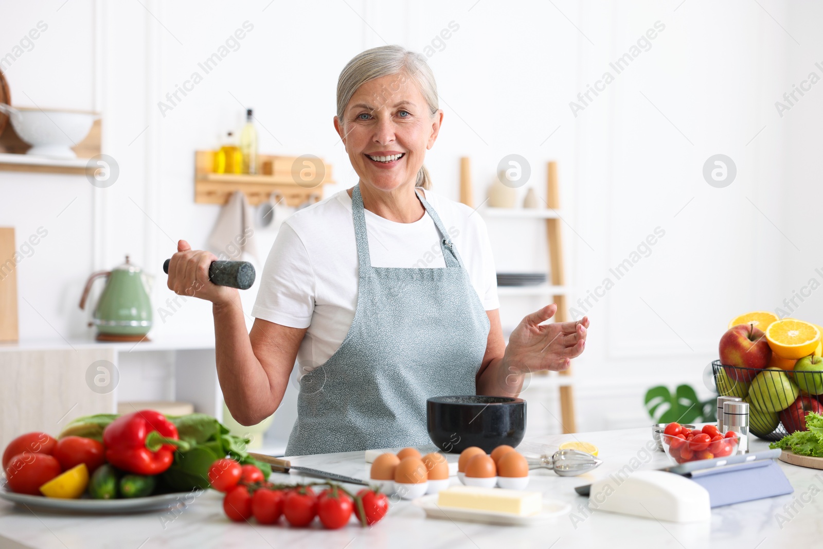 Senior woman cooking at white marble table in kitchen Photo of Senior woman cooking at white marble table in kitchen