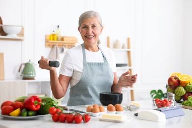 Photo of Senior woman cooking at white marble table in kitchen