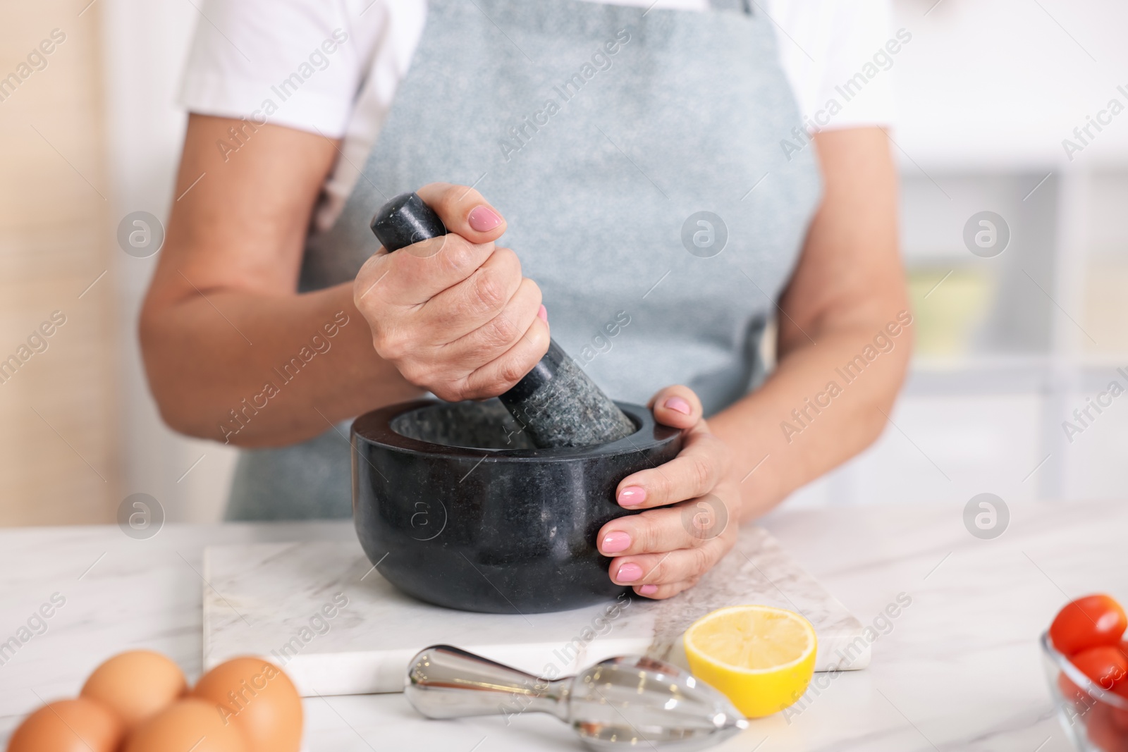 Senior woman cooking at white marble table in kitchen, closeup Photo of Senior woman cooking at white marble table in kitchen, closeup