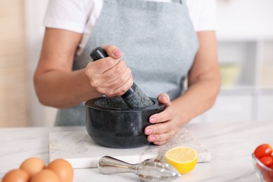 Photo of Senior woman cooking at white marble table in kitchen, closeup