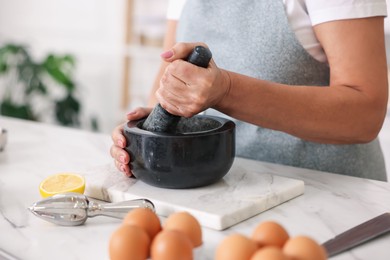Photo of Senior woman cooking at white marble table in kitchen, closeup