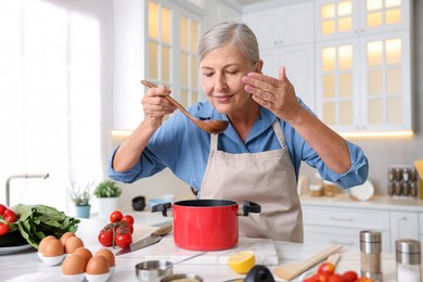 Photo of Senior woman cooking at white marble table in kitchen