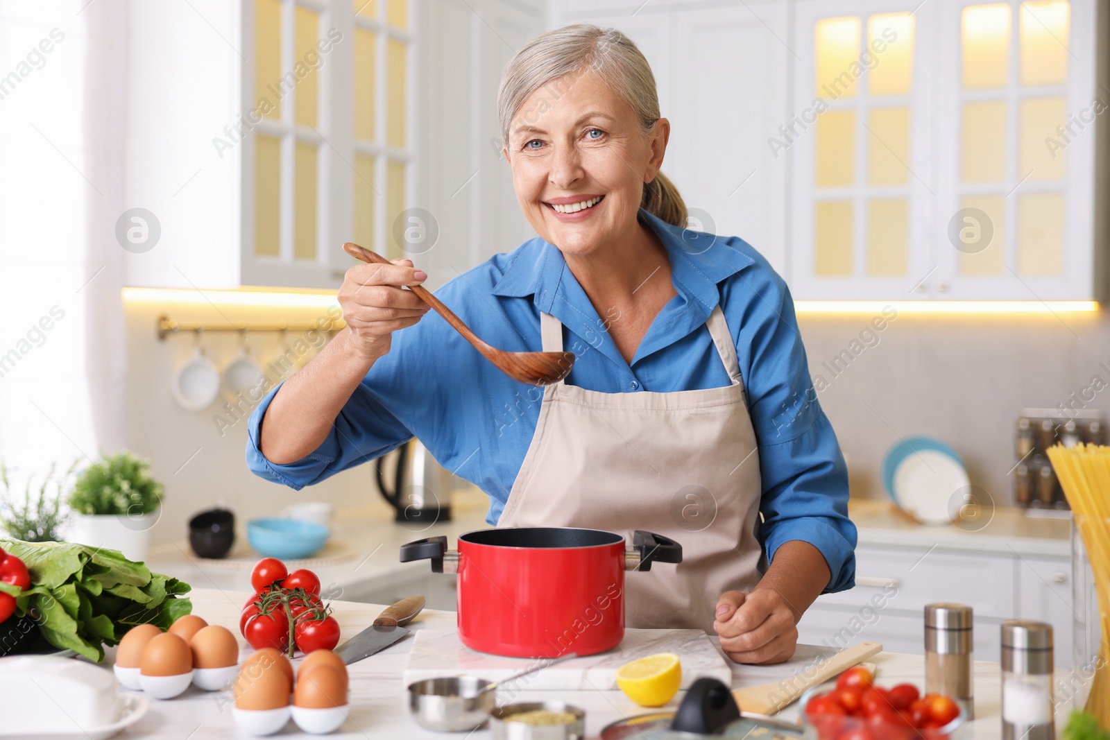 Senior woman cooking at white marble table in kitchen Photo of Senior woman cooking at white marble table in kitchen