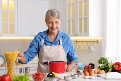 Photo of Senior woman cooking at table in kitchen