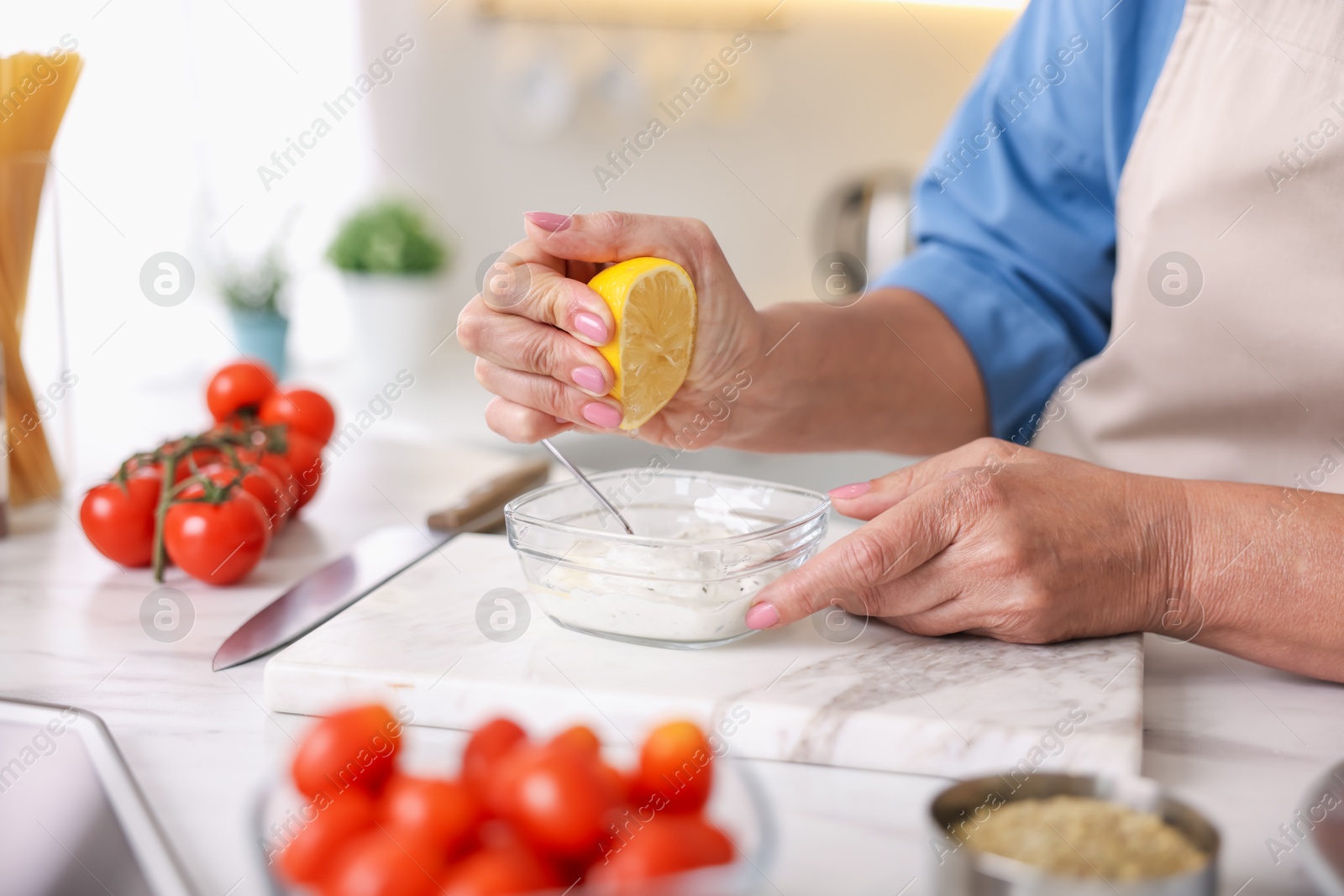 Senior woman cooking at white marble table in kitchen, closeup Photo of Senior woman cooking at white marble table in kitchen, closeup