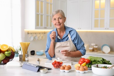 Photo of Senior woman cooking at white marble table in kitchen