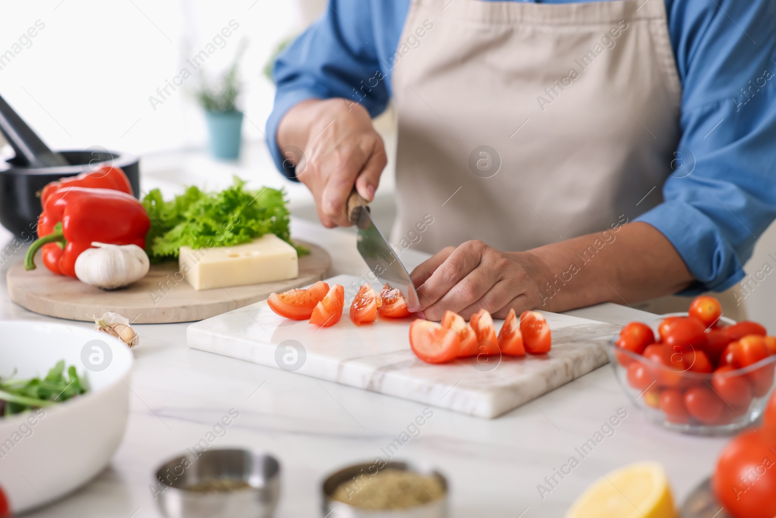 Senior woman cooking at white marble table in kitchen, closeup Photo of Senior woman cooking at white marble table in kitchen, closeup