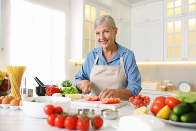 Photo of Senior woman cooking at table in kitchen
