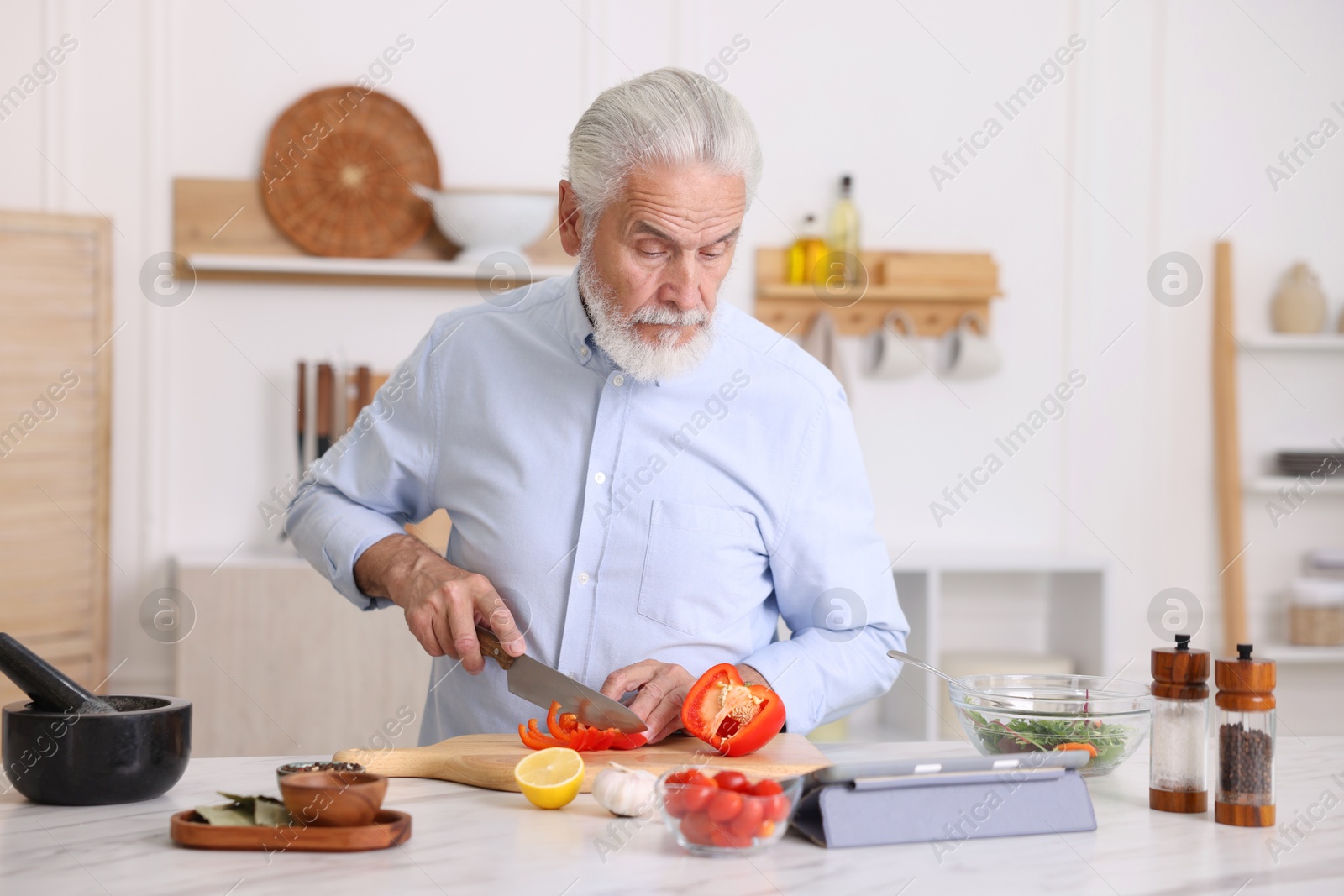 Elderly man cooking at white marble table in kitchen Photo of Elderly man cooking at white marble table in kitchen