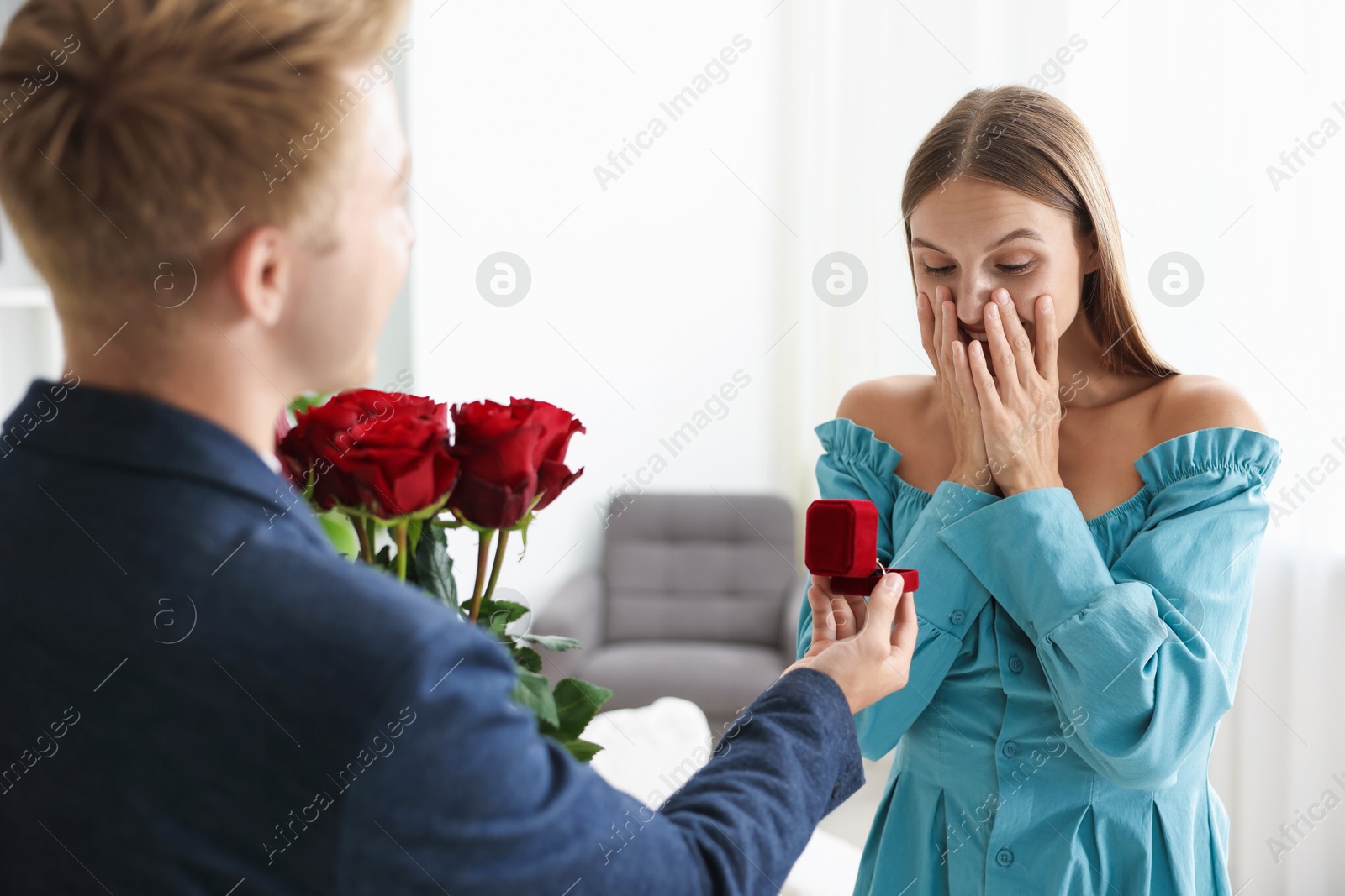 Man with engagement ring and bouquet of roses making marriage proposal to his happy girlfriend at home Photo of Man with engagement ring and bouquet of roses making marriage proposal to his happy girlfriend at home